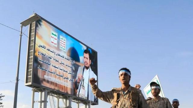 Combatientes hutíes desfilan junto a un cartel en el que aparece el líder de los hutíes, Abdul Malik al-Houthi, en una calle de Saná, Yemen.