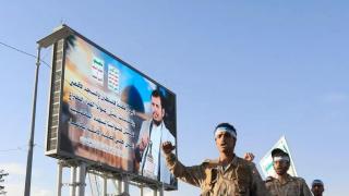 Combatientes hutíes desfilan junto a un cartel en el que aparece el líder de los hutíes, Abdul Malik al-Houthi, en una calle de Saná, Yemen.