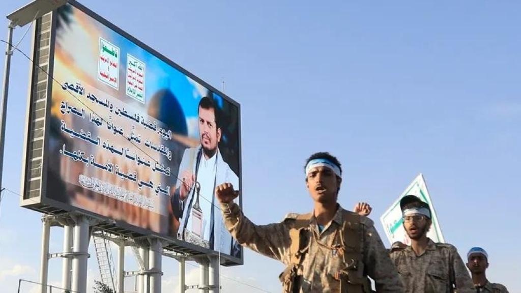 Combatientes hutíes desfilan junto a un cartel en el que aparece el líder de los hutíes, Abdul Malik al-Houthi, en una calle de Saná, Yemen.