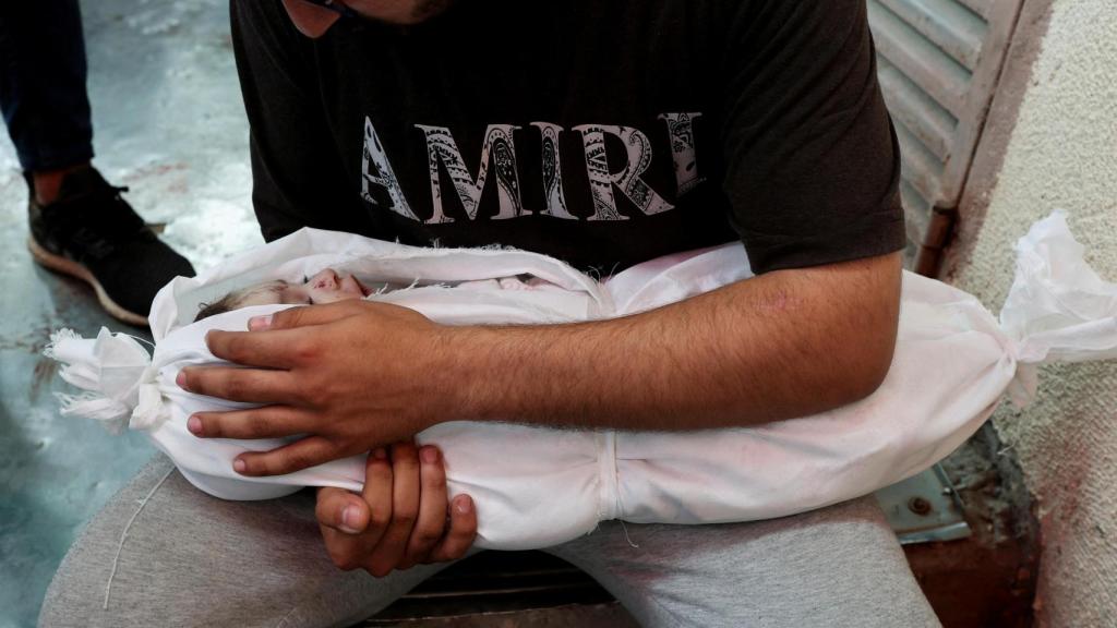 Una padre sostiene a su hijo muerto por los ataques de Israel este domingo en Deir Al-Balah, en el centro de la Franja de Gaza.