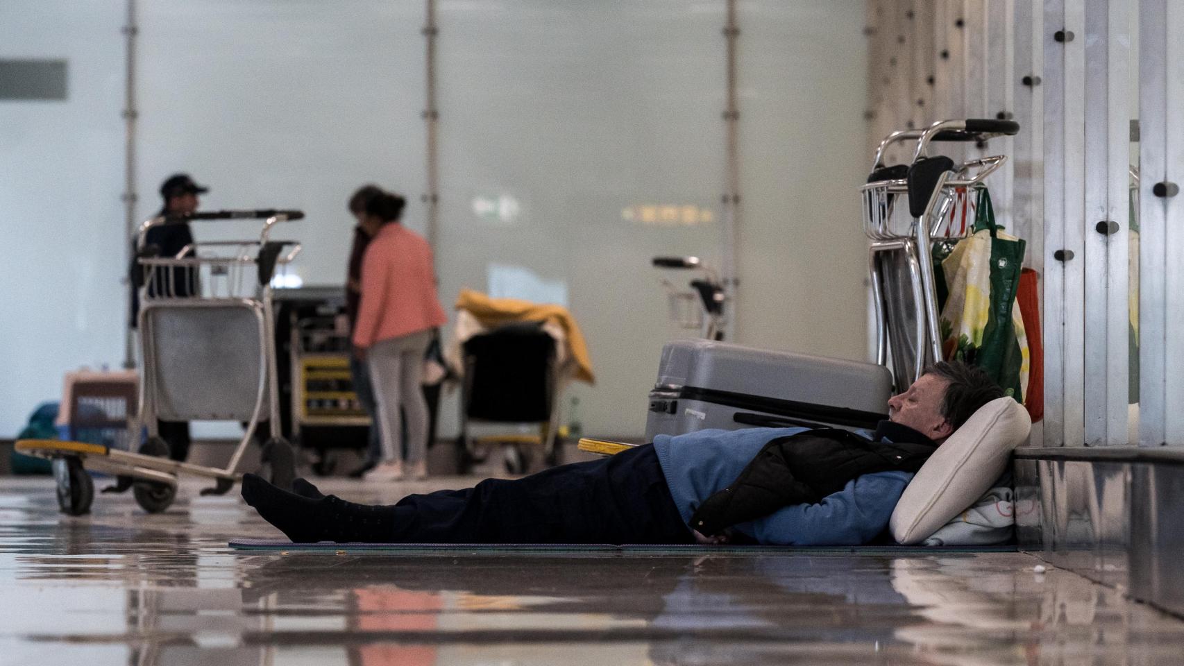 Un hombre tumbado en el suelo en la T4 del Aeropuerto Adolfo Suárez-Madrid Barajas, a 12 de mayo de 2025, en Madrid (España).