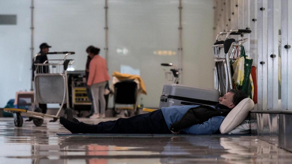 Un hombre tumbado en el suelo en la T4 del Aeropuerto Adolfo Suárez-Madrid Barajas, a 12 de mayo de 2025, en Madrid (España).