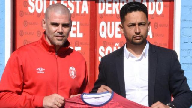Víctor Valdés en su presentación, junto con Joan Farias, director deportivo del Real Ávila, posando con una camiseta del club.