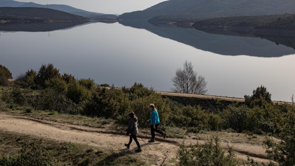 Dos personas haciendo senderismo a orillas del embalse de El Atazar.