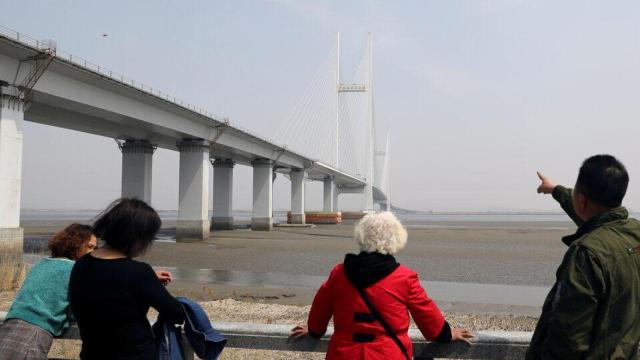 Un hombre señala al puente sin finalizar entre China y Corea del Norte, en Dandong (China).