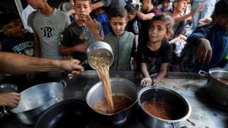 Niños gazatíes esperan a que una oenegé les sirva una ración de comida.
