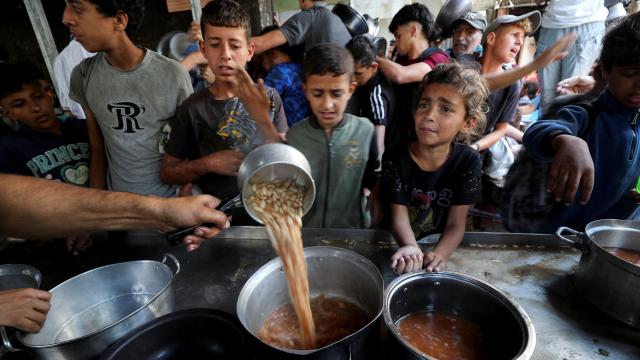 Niños gazatíes esperan a que una oenegé les sirva una ración de comida.