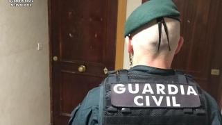 Un agente de la Guardia Civil ante la puerta con los disparos en la vivienda del municipio palentino de Villamuriel de Cerrato