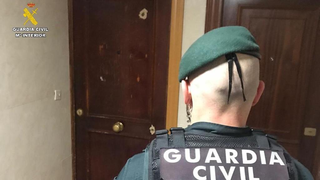 Un agente de la Guardia Civil ante la puerta con los disparos en la vivienda del municipio palentino de Villamuriel de Cerrato
