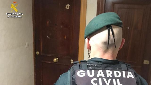 Un agente de la Guardia Civil ante la puerta con los disparos en la vivienda del municipio palentino de Villamuriel de Cerrato