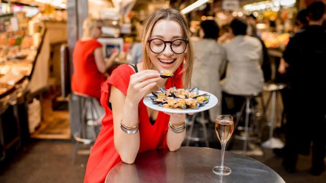 Mujer comiendo mejillones.