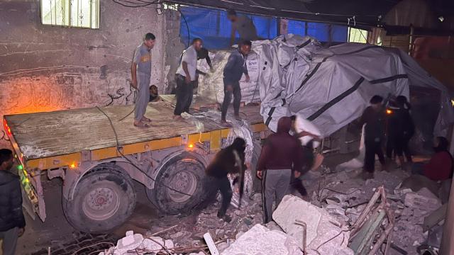 Trabajadores palestinos descargan un camión con ayuda humanitaria en Jan Yunis.