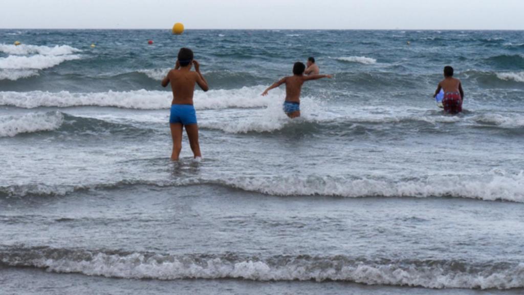 Imagen de archivo de un grupo de menores que se introduce en el agua con oleaje.