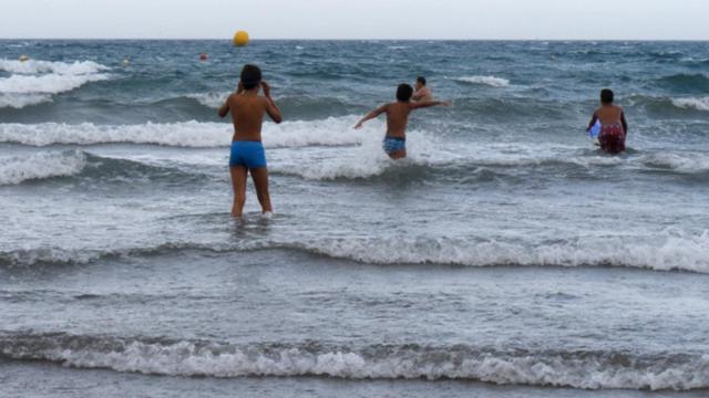 Imagen de archivo de un grupo de menores que se introduce en el agua con oleaje.