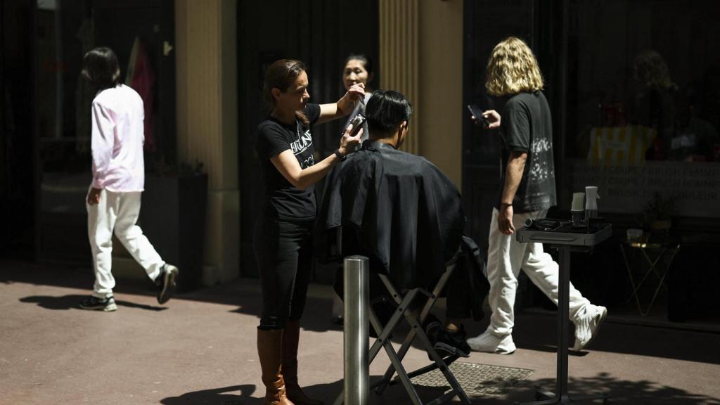 Una peluquera corta el pelo a una clienta en la calle debido a la falta de luz en su peluquería en Cannes.