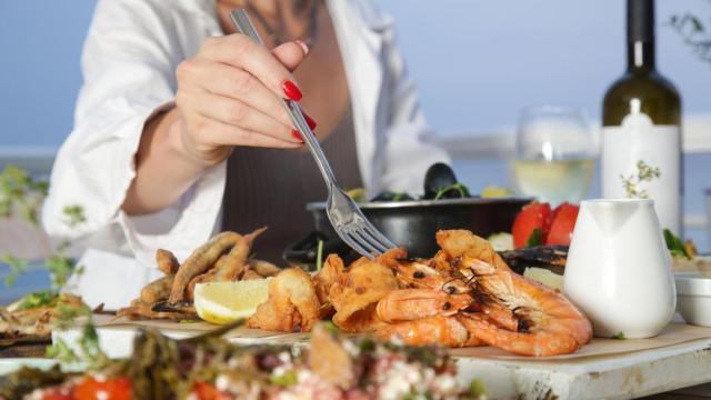 Mujer comiendo marisco.