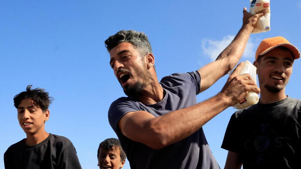 Una persona sostiene alimentos mientras los palestinos se reúnen cerca de un centro de distribución de ayuda dirigido por la Fundación Humanitaria de Gaza en el sur de la Franja de Gaza, el 27 de mayo de 2025.