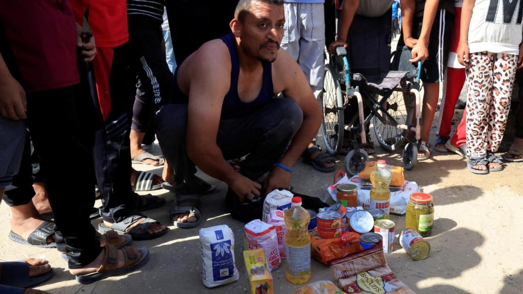Una persona se arrodilla junto a suministros de alimentos mientras los palestinos que buscan ayuda se reúnen cerca de un sitio de distribución de ayuda administrado por la Fundación Humanitaria de Gaza respaldada por Estados Unidos , en Rafah, en el sur de la Franja de Gaza, el 27 de mayo de 2025