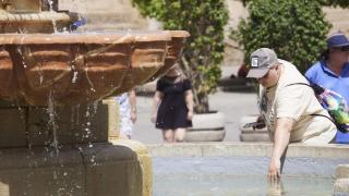 Una persona introduce la mano en una fuente para refrescarse.
