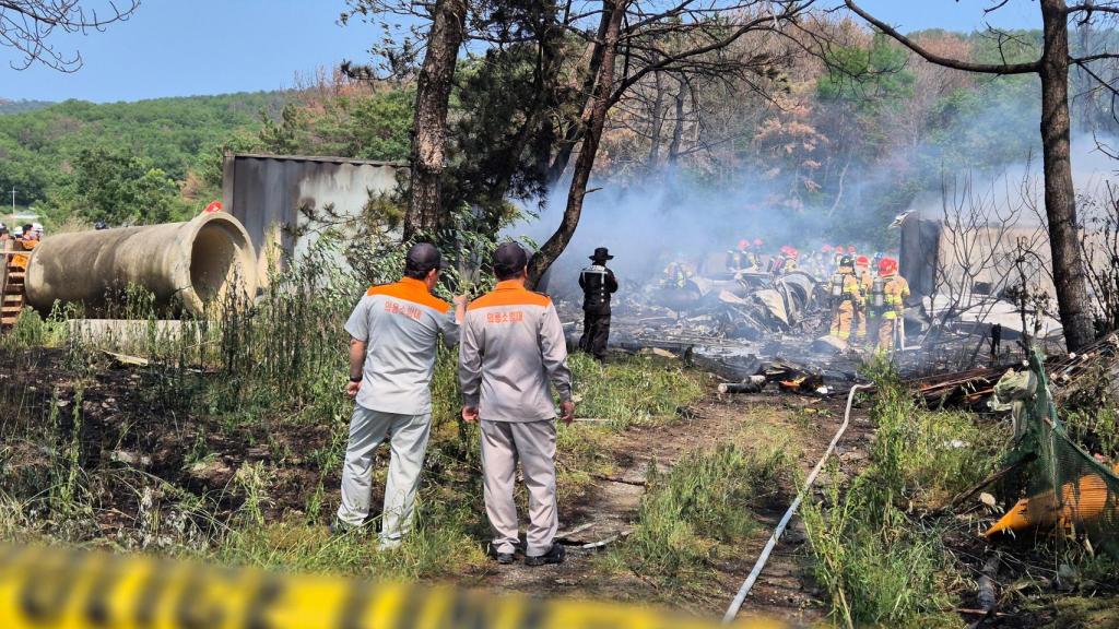 Bomberos surcoreanos apagando las llamas provocadas por el accidente del avión.