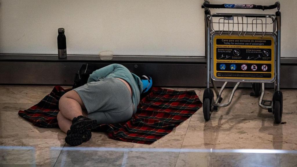 Una persona duerme en la T4 del Aeropuerto Adolfo Suárez-Madrid Barajas, a 12 de mayo de 2025, en Madrid