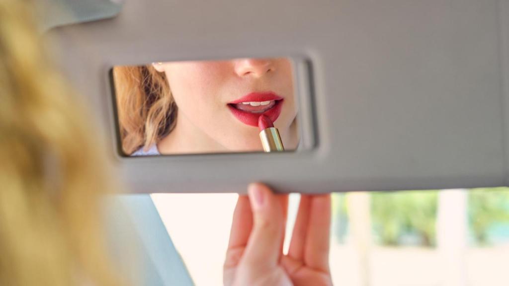 Una mujer se pinta los labios en el coche