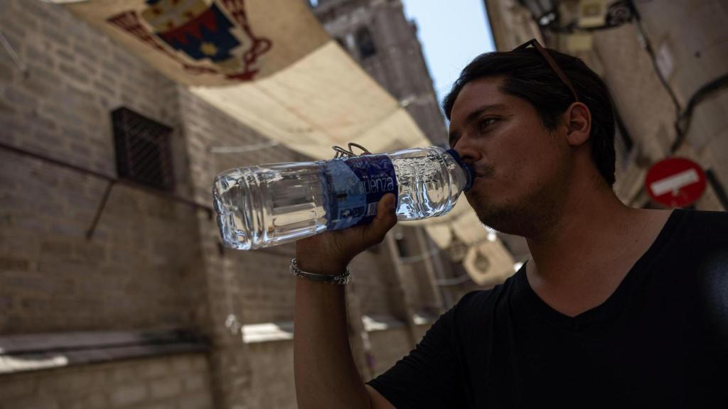 Toledanos y turistas se protegen del calor buscando sombras y bebiendo por las calles de Toledo.