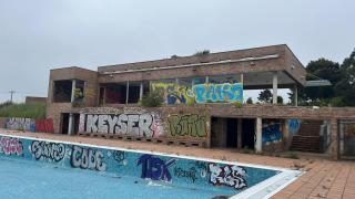 Vecinos de la urbanización posan ante la entrada de las instalaciones deportivas abandonadas de Montegolf, en A Coruña