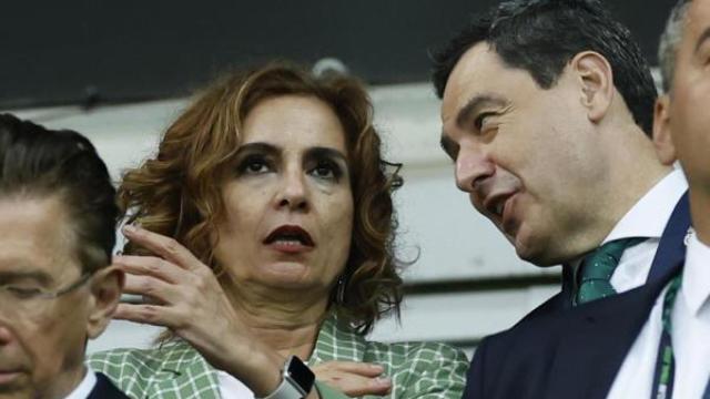 La vicepresidenta del Gobierno, María Jesús Montero, junto al presidente de la Junta, Juanma Moreno, en el partido del Betis en Polonia.