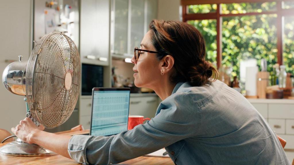Mujer acercándose a un ventilador.