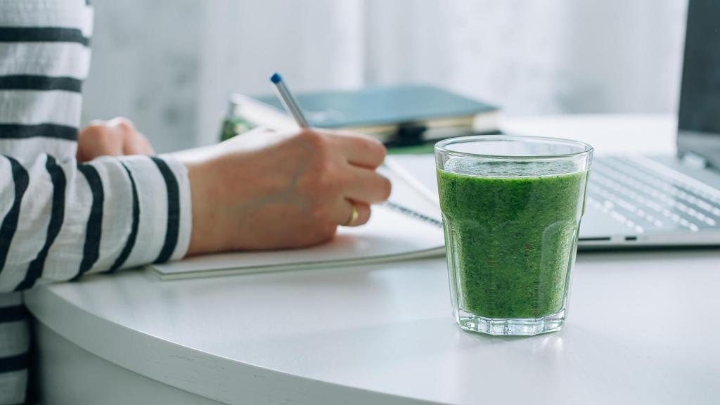 Una persona estudiando y tomando un batido.