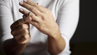 Mujer quitándose su anillo de casada.