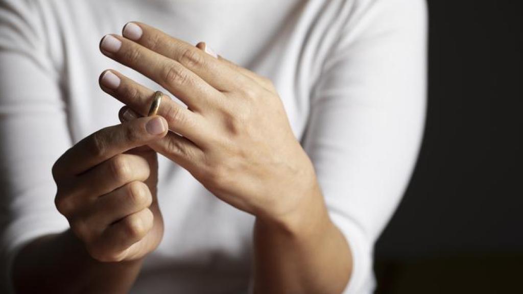 Mujer quitándose su anillo de casada.