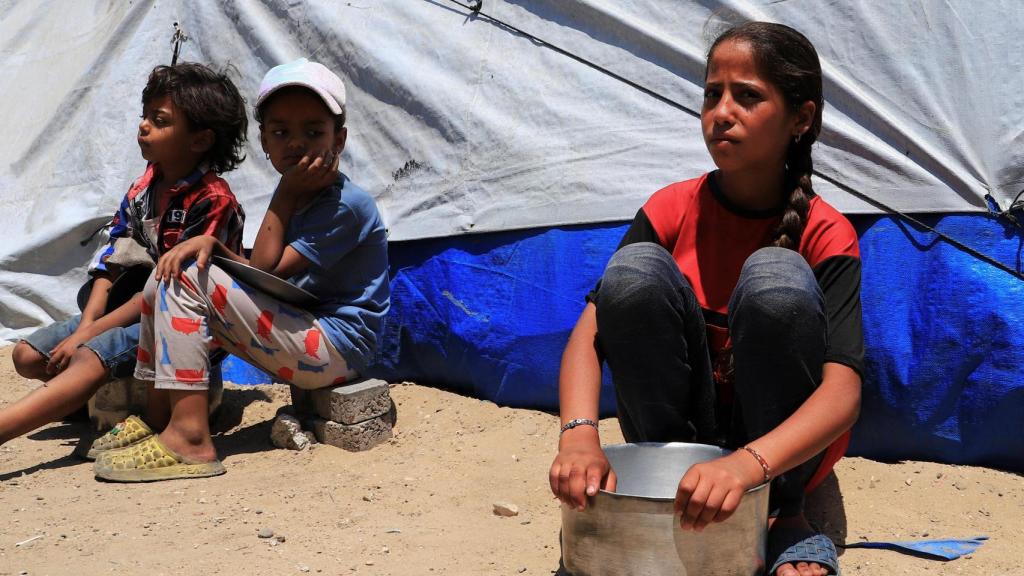 Niños palestinos desplazados, uno de ellos con una olla vacía, esperan recibir comida de un comedor social en la ciudad de Gaza , el 3 de junio de 2025.