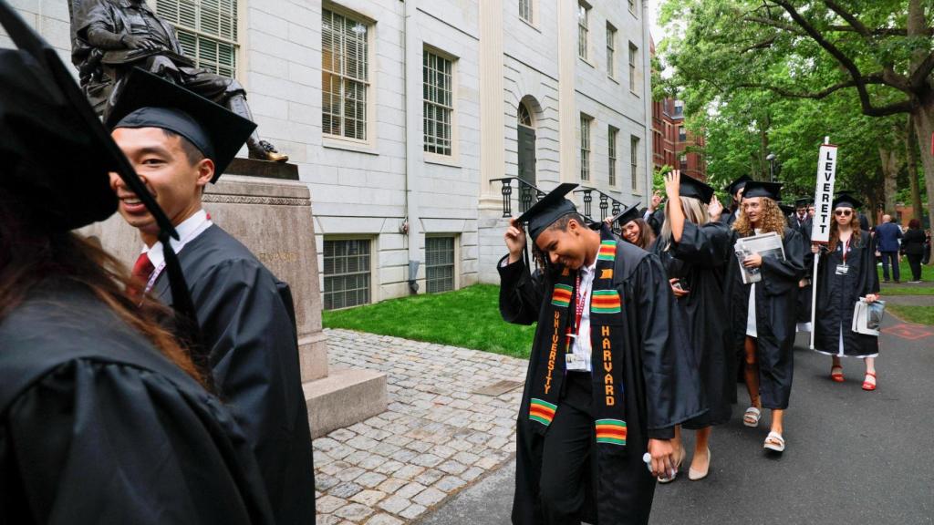 Estudiantes de la universidad de Harvard desfilan ante la estatua de John Harvard.