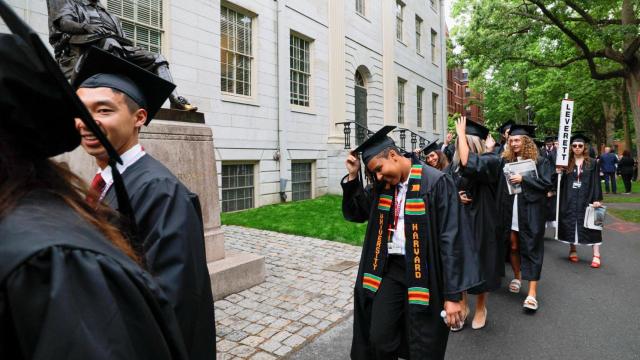 Estudiantes de la universidad de Harvard desfilan ante la estatua de John Harvard.