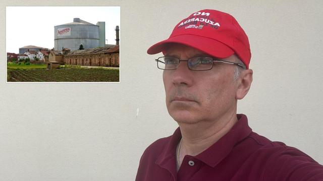 Miguel Santos, trabajador afectado por el cierre de Azucarera junto a una imagen de la planta de La Bañeza (Leon)