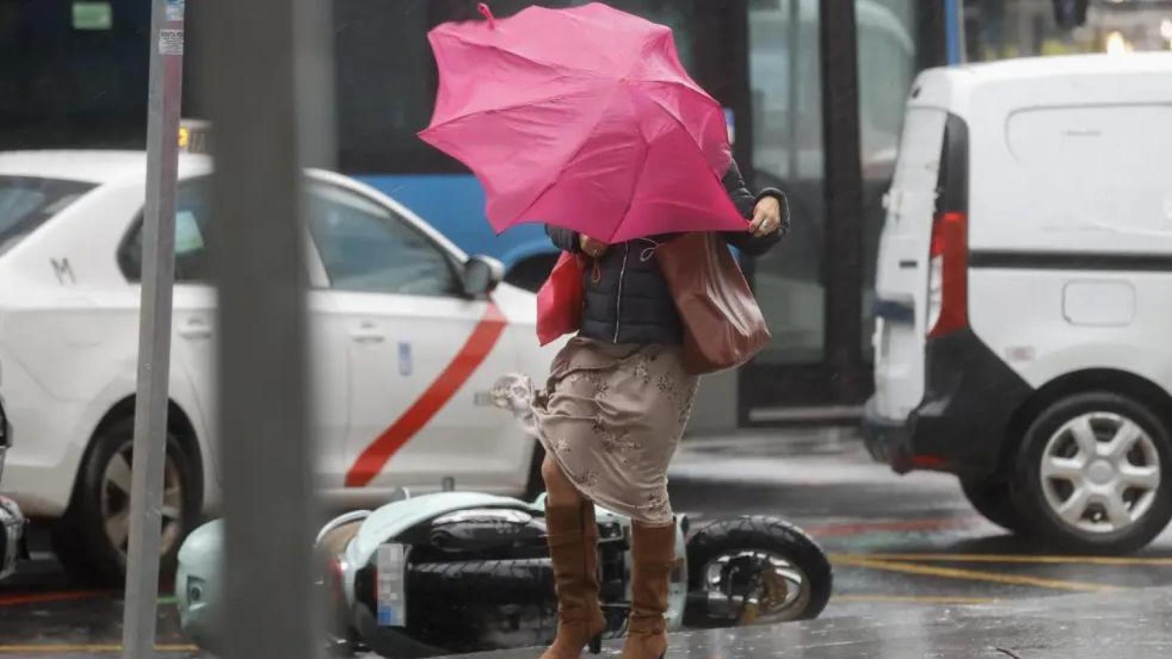 Una mujer se protege del fuerte viento.