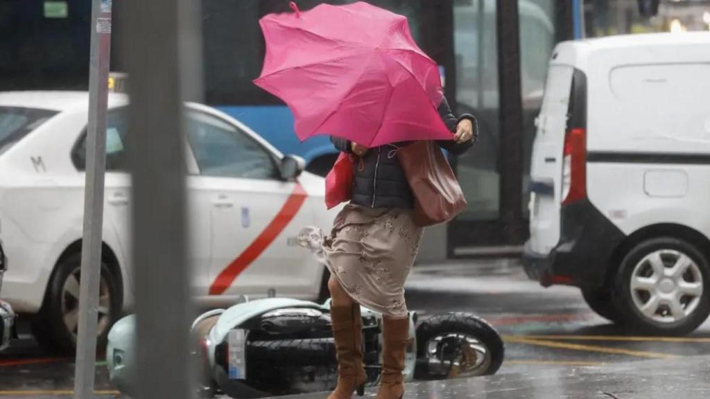 Una mujer se protege del fuerte viento en Madrid.