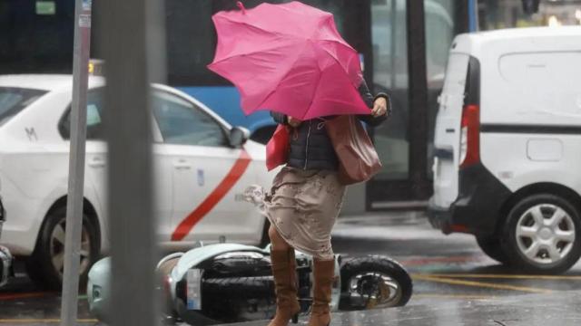 Una mujer se protege del fuerte viento en Madrid.