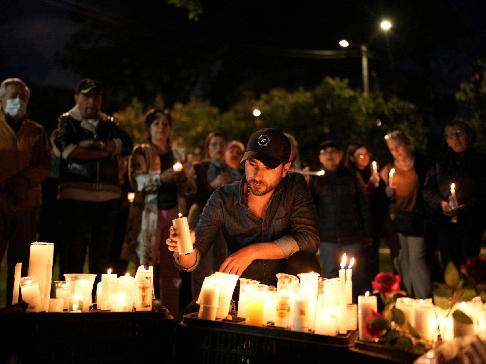 Personas colocan velas en el lugar donde el senador colombiano Miguel Uribe Turbay fue baleado durante un acto de campaña, en Bogotá.