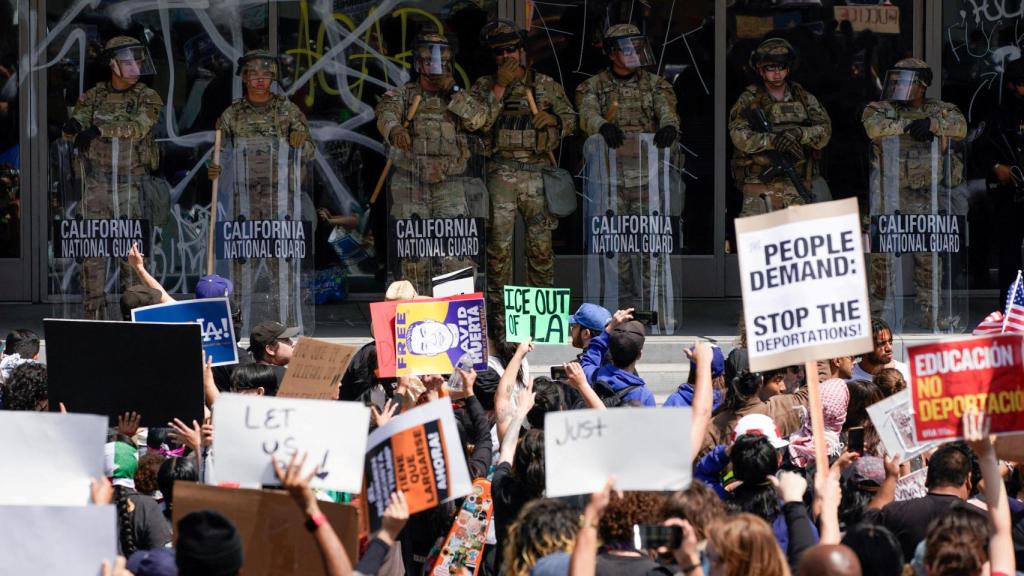 Tropas de la Guardia Nacional de California y un oficial de policía hacen guardia mientras la gente asiste a una manifestación contra las redadas federales de inmigración, en el centro de Los Ángeles, California, EE. UU., el 9 de junio de 2025.