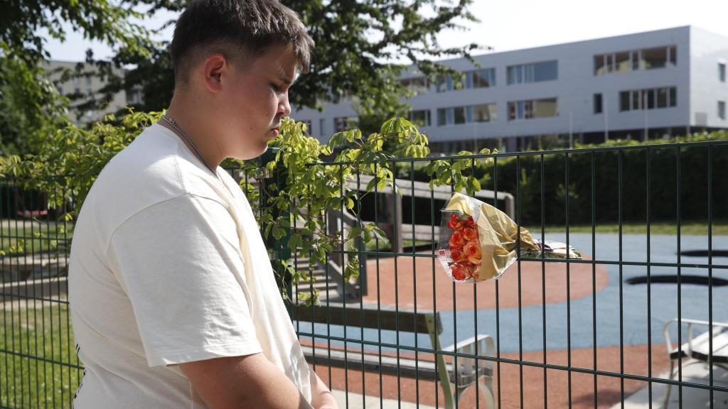 Un joven coloca un ramo de flores en una de las verjas del instituto BORG.