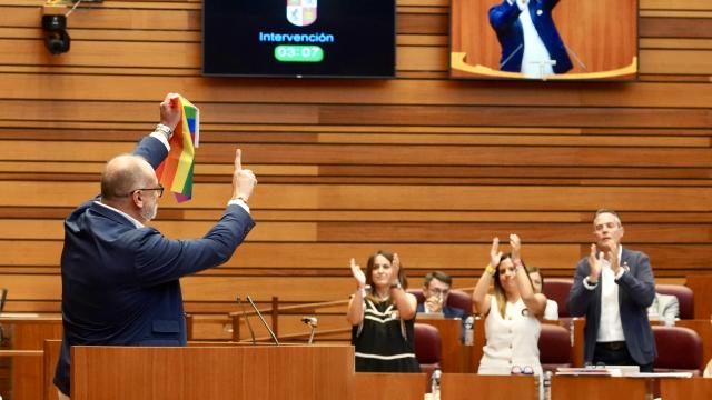 El procurador socialista Miguel Hernández Alcojor enarbola la bandera LGTBI en las Cortes durante la presentación de la proposición de Ley, en el pleno de este miércoles