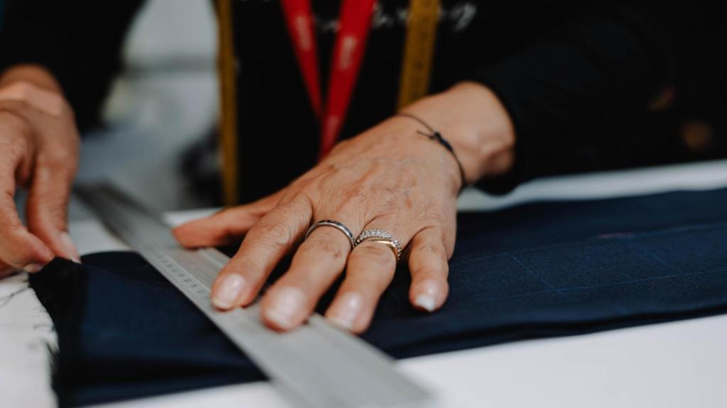 Detalle de las manos de una trabajadora de la sastrería mientras confecciona una de sus piezas.
