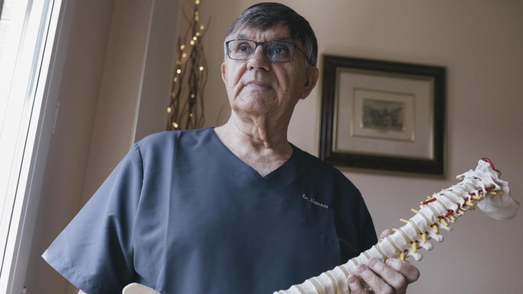 Antonio Luis Mostaza, el neurocirujano de los toreros, sostiene una réplica de columna vertebral.