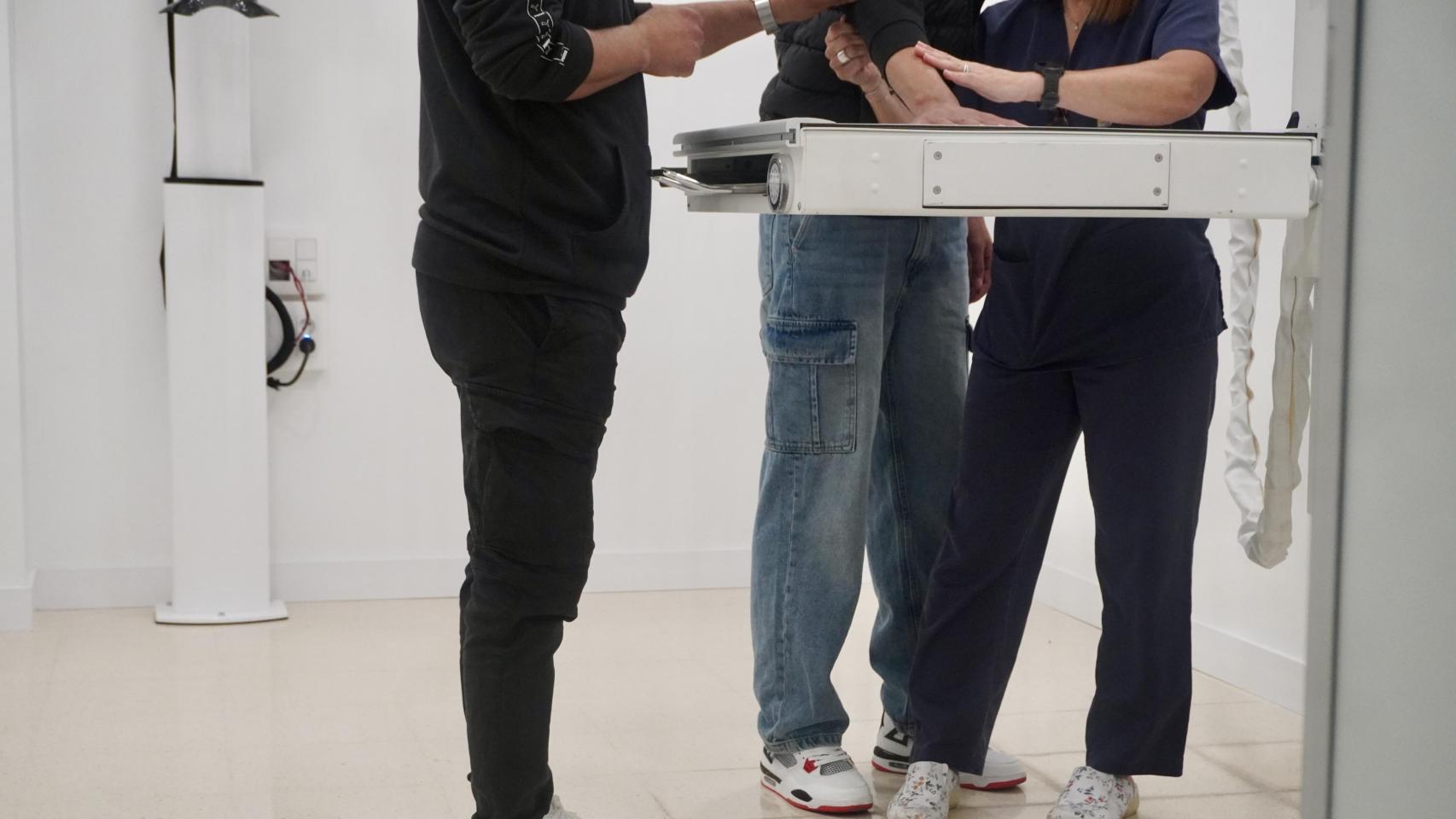 La Dr. García muestra a uno de los migrantes y al intérprete cómo debe colocar su mano para poder realizar la prueba.