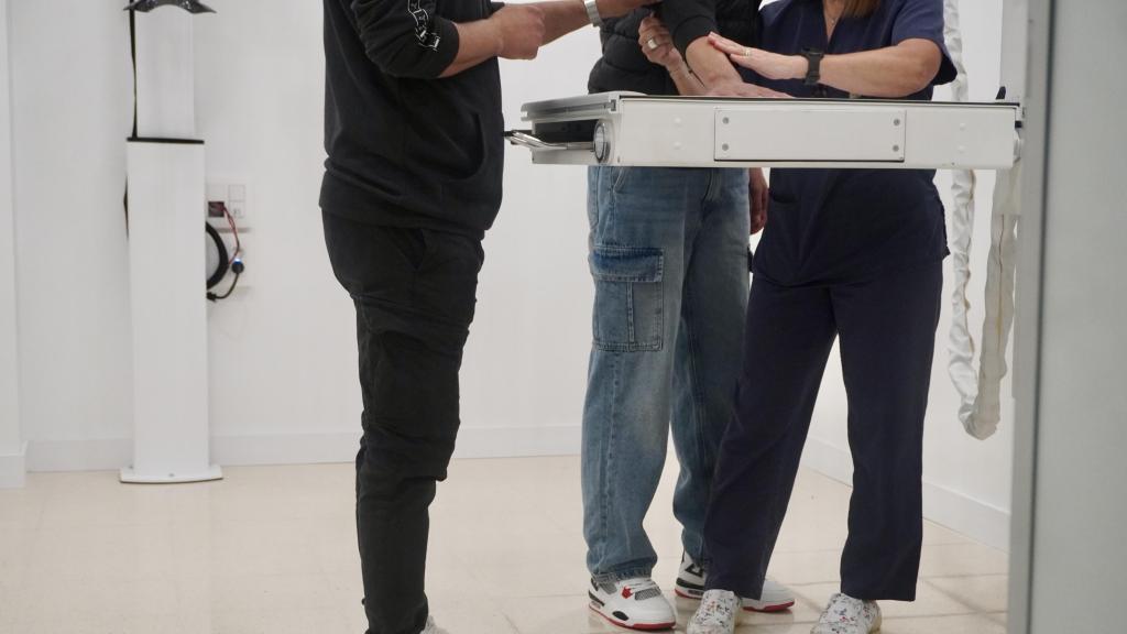 La Dr. García muestra a uno de los migrantes y al intérprete cómo debe colocar su mano para poder realizar la prueba.