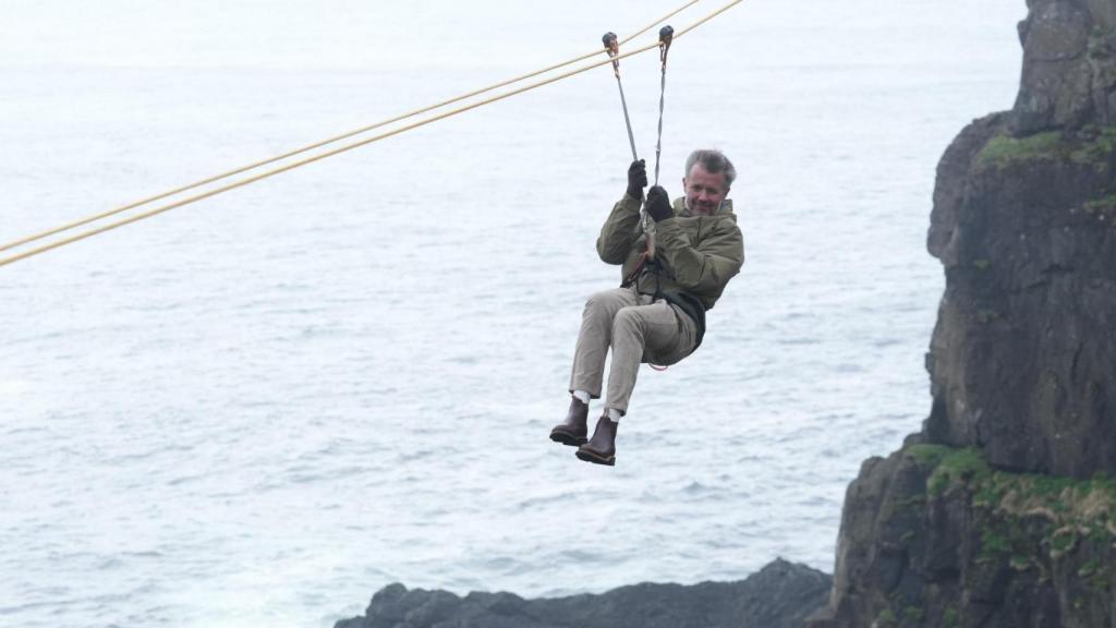El rey Federico de Dinamarca, subido a una tirolina en las islas Feroe.