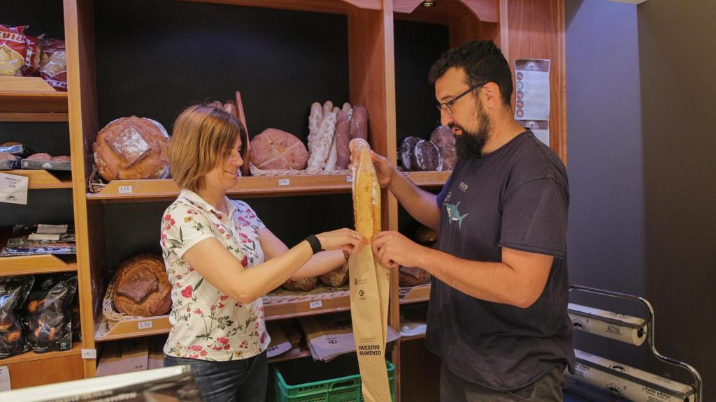 Entrega de una bolsa de pan en una tienda tradicional de la provincia de Segovia